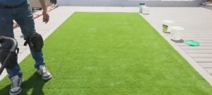 A professional installing artificial turf with knee pads, ensuring precision and durability. Achieve a flawless lawn installation today!