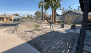 Spreading gravel in a front yard landscape project. Hire a professional contractor to transform your yard with expert precision.