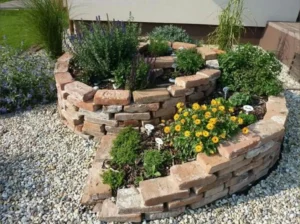 Brick spiral herb garden with colorful flowers, designed to add beauty and functionality to your landscape. Contact Design Build AZ to transform your outdoor space.